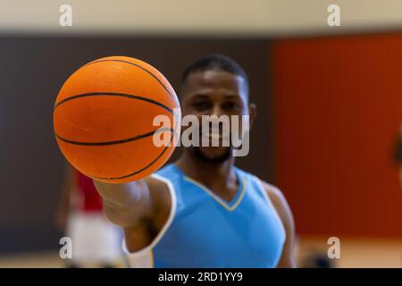 Portrait eines glücklichen afroamerikanischen Basketballspielers, der Basketball im Fitnessstudio hält Stockfoto