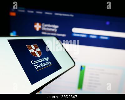 Smartphone mit Logo von Cambridge Dictionary auf dem Bildschirm vor der Website. Fokus auf der linken Seite des Telefondisplays. Stockfoto