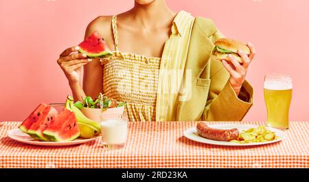 Frau isst gesunde Lebensmittel, Vitamine, Mann isst Junk Food, Burger und Bier vor pinkfarbenem Studiohintergrund Stockfoto