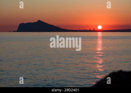 Silhouette der Wolkenkratzer der Stadt Benidorm bei Sonnenuntergang von Calpe, Spanien aus gesehen Stockfoto