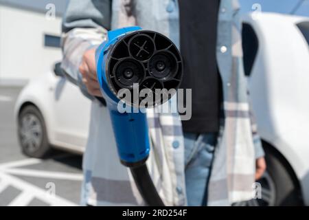 Frau mit Schnellladesteckdose CHAdeMO. Steckverbinder Batterie Elektrofahrzeug an EV-Station, Gleichstrom DC. Kfz-Ladegerät anschließen. Stockfoto