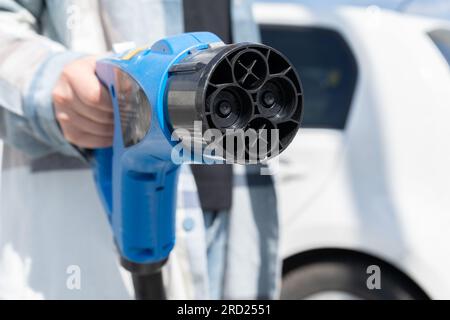 Frau mit Schnellladesteckdose CHAdeMO. Steckverbinder Batterie Elektrofahrzeug an EV-Station, Gleichstrom DC. Kfz-Ladegerät anschließen. Stockfoto