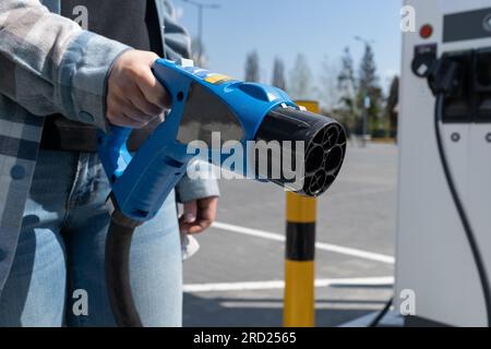 Frau mit Schnellladesteckdose CHAdeMO. Steckverbinder Batterie Elektrofahrzeug an EV-Station, Gleichstrom DC. Kfz-Ladegerät anschließen. Stockfoto