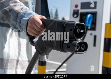 Frau mit CCS-Buchse Typ 2. Schnelles kombiniertes Ladesystem Combo 2-Anschlussstecker für Elektrofahrzeuge an der EV-Station. Kfz-Ladegerät anschließen. Stockfoto