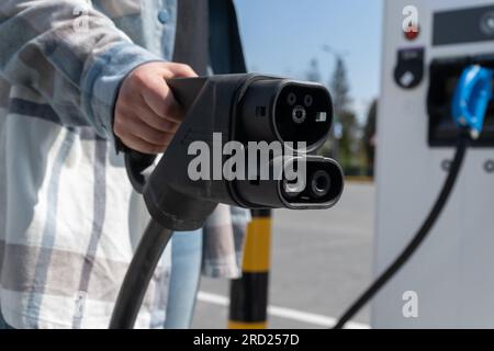 Frau mit CCS-Buchse Typ 2. Schnelles kombiniertes Ladesystem Combo 2-Anschlussstecker für Elektrofahrzeuge an der EV-Station. Kfz-Ladegerät anschließen. Stockfoto