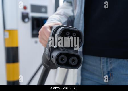 Frau mit CCS-Buchse Typ 2. Schnelles kombiniertes Ladesystem Combo 2-Anschlussstecker für Elektrofahrzeuge an der EV-Station. Kfz-Ladegerät anschließen. Stockfoto