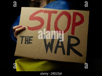 Frau mit ukrainischer Flagge und Schild "Stopp den Krieg". Protest gegen die russische Invasion der Ukraine. Russischer Angriff, Anti-Kriegs-Demonstration. Stockfoto