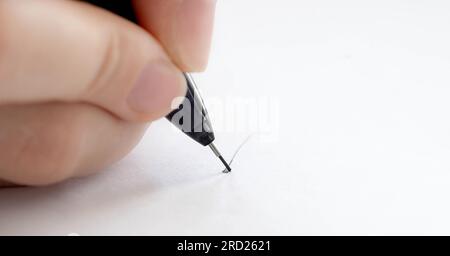 Person hält Stift und schreibt auf weißes Papier Nahaufnahme. Finger mit Bleistift zeichnen in einer leeren Makroansicht Stockfoto