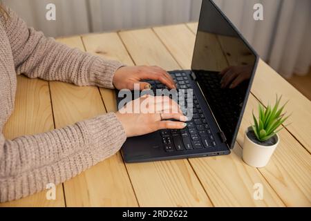 Nahaufnahme von Frauen, die mit der Hand tippen. Frau, die den Laptop zu Hause benutzt Stockfoto