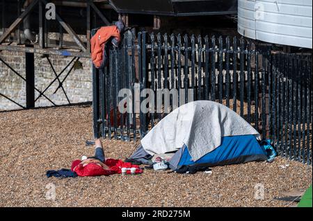 Brighton UK 18. Juli 2023 - Menschen, die an einem heißen, sonnigen Morgen an der Südküste in Zelten am Brighton Beach am Pier schlafen : Credit Simon Dack / Alamy Live News Stockfoto