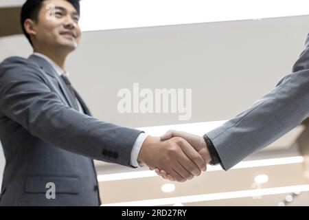 Erfolgreiche chinesische Geschäftsleute, die im Amt die Hand schütteln Stockfoto