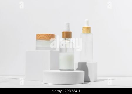 Kosmetikverpackungen. Set aus verschiedenen Kosmetikgefäßen und Tuben mit Creme auf weißen Podien. Leere Verpackung. Natürliches Beauty-Spa-Produktkonzept. Beauty.M Stockfoto