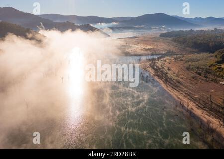 Nebelstellen am Ufer eines Sees, umgeben von Bergen am Lake Eildon in Victoria, Australien, aus der Vogelperspektive Stockfoto