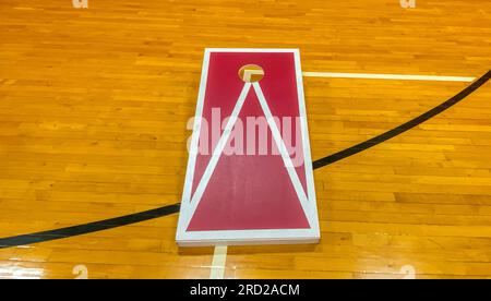 Ein rot-weißes, hausgemachtes Maisloch-Brett aus der Nähe eines Gymnastikbodens der Highschool. Stockfoto