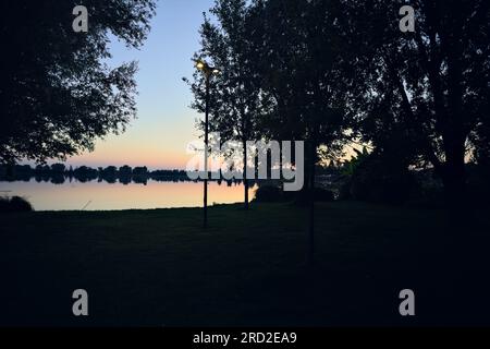 Lampen am Flussufer in einem Park bei Sonnenuntergang Stockfoto