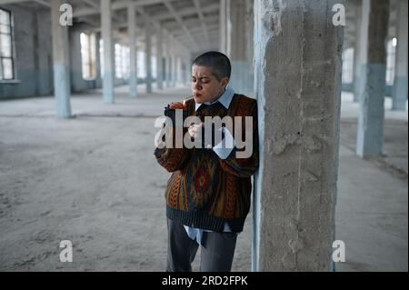 Obdachlose Punk-Frau, die kaum auf den Füßen stand, lehnte sich an die Säule Stockfoto