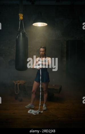 Eine starke Sportlerin, die sich die Hände mit Boxverbänden einwickelt Stockfoto