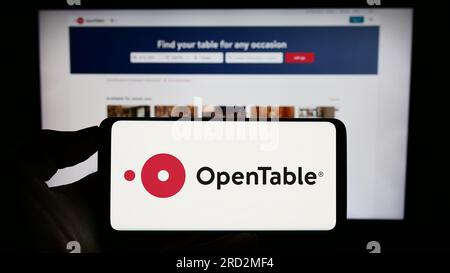 Person, die ein Mobiltelefon mit dem Logo des US-amerikanischen Reservierungsdienstleisters OpenTable Inc. Auf dem Bildschirm vor der Webseite hält. Konzentrieren Sie sich auf das Display des Telefons. Stockfoto