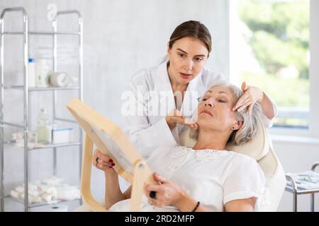 Der ältere Patient sieht in der Klinik in den Spiegel. Stockfoto