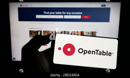 Person, die ein Mobiltelefon mit dem Logo des amerikanischen Reservierungsdienstleisters OpenTable Inc. Auf dem Bildschirm vor der Webseite hält. Konzentrieren Sie sich auf das Display des Telefons. Stockfoto