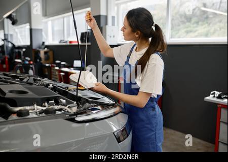 Junge Technikerin zur Ölstandsprüfung in der Kfz-Werkstatt Stockfoto