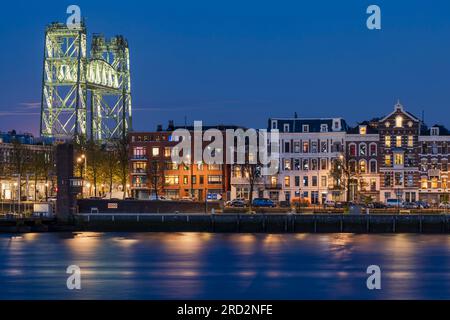 Der nördliche Maaskade-Kai in Rotterdam mit der historischen Eisenbahnbrücke am Abend Stockfoto