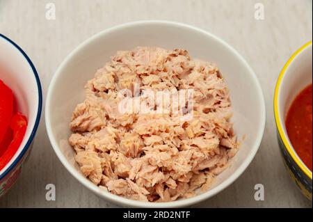 Thunfisch in der Schüssel in der Draufsicht isoliert auf hellem Hintergrund. Stockfoto