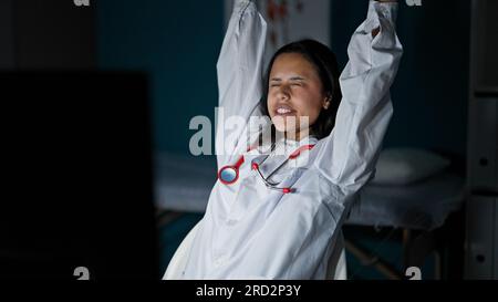 Junge, wunderschöne hispanische Ärztin, die Arme in der Klinik streckt Stockfoto
