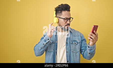 Junger lateiner, der Musik auf einem isolierten gelben Hintergrund hört Stockfoto