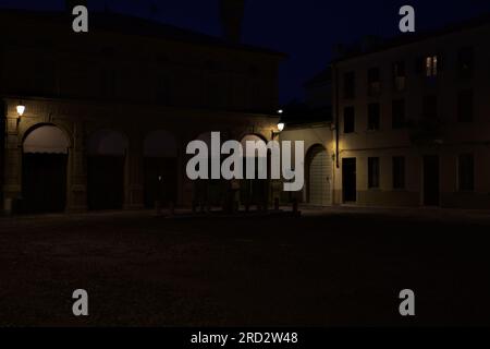 Ein von Lampen beleuchteter Platz mit einem Springbrunnen in der Mitte in einer italienischen Stadt bei Einbruch der Dunkelheit Stockfoto