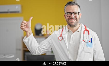 Ein grauhaariger Arzt, der in der Klinik Daumen hoch hält Stockfoto