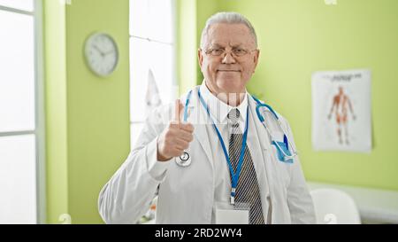 Mittelalter, grauhaariger Arzt, der in der Klinik Daumen hoch macht Stockfoto