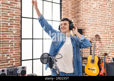 Junger nicht binärer Künstler, der Musik beim Tanzen im Musikstudio lauscht Stockfoto