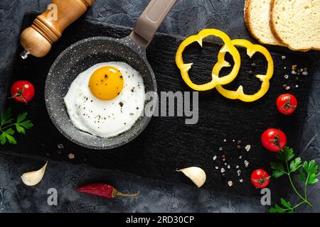 Spiegeleier in einer Pfanne mit frischem Gemüse und Gewürzen. Konzept für Speisekarte und Werbung. Stockfoto