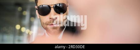 Stop-Geste, Bodyguard in dunkler Sonnenbrille und schwarzer Anzug, der in die Kamera schaut, Halt zeigt, Hotelsicherheit, Sicherheitsmanagement, uniformierter Wachmann im Dienst, Stockfoto