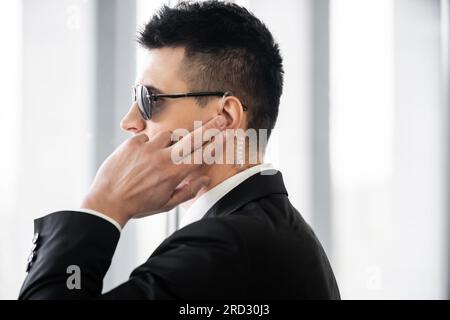 Professionelle Kopfschüsse, Bodyguard kommuniziert über Ohrhörer, Mann mit Sonnenbrille und schwarzem Anzug mit Krawatte, Hotelsicherheit, Sicherheitsmanagement, Überwachung Stockfoto