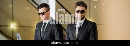 Sicherheitsmanagement eines Luxushotels, zwei gutaussehende Männer in formeller Kleidung und Sonnenbrille, Leibwächter im Dienst, Sicherheitsmaßnahmen, Wachsamkeit, Anzüge und Krawatten, P Stockfoto