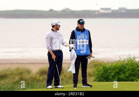 Patrick Cantlay (links) der USA und Caddie Joe LaCaza auf dem 17. Green mit Blick auf Hilbre Island und den River Dee während einer Übungsrunde vor den Open im Royal Liverpool, Wirral. Bilddatum: Dienstag, 18. Juli 2023. Stockfoto