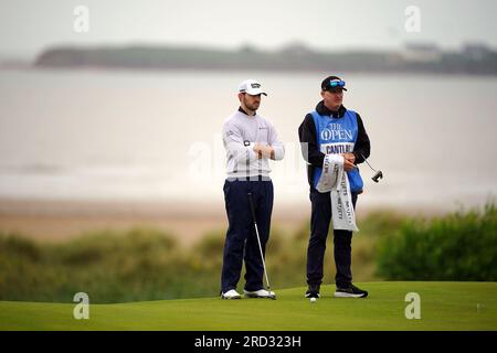 Patrick Cantlay (links) der USA und Caddie Joe LaCaza auf dem 17. Green mit Blick auf Hilbre Island und den River Dee während einer Übungsrunde vor den Open im Royal Liverpool, Wirral. Bilddatum: Dienstag, 18. Juli 2023. Stockfoto