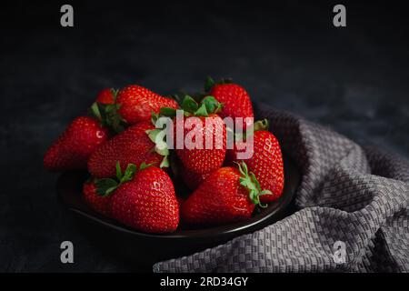 Strawbarry mit grauer Serviette auf schwarzem Hintergrund. Süße Farben für soziale Medien Stockfoto