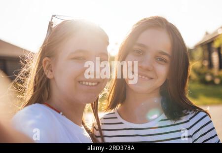 Zwei süße Teenager-Mädchen lächeln und posieren für die Kamera. Reizende Teenager-Freundinnen in lässiger Kleidung machen Selfies im Freien. Süße Teenager haben eine gute Zeit Stockfoto