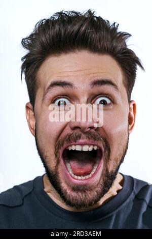 Junger verrückter Mann emotionales Wow-Porträt auf weißem Hintergrund Stockfoto