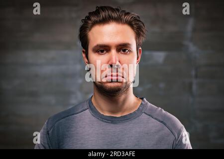 Ein junger, gutaussehender Mann hat das Porträt auf grauem Hintergrund verärgert Stockfoto