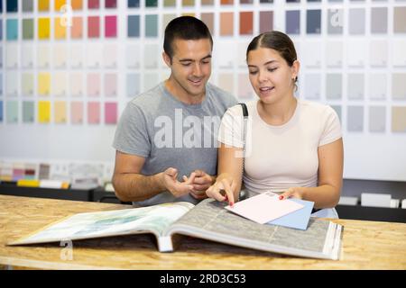 Ein Ehepaar wählt die Farbe der Keramikfliesen aus dem Katalog im Baumarkt Stockfoto