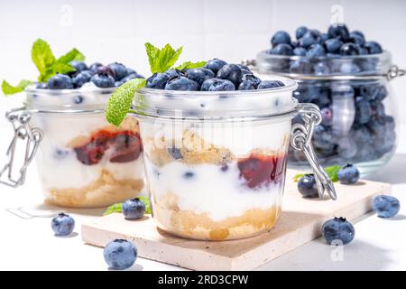 Mehrschichtiges Blaubeerparfait-Dessert, Käsekuchen im Glas mit Vanillekekuchen, cremiger Joghurt, Marmelade und frischer Blaubeere Stockfoto