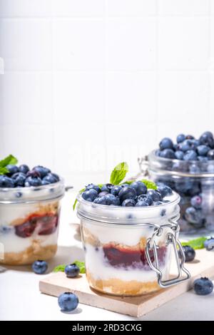 Mehrschichtiges Blaubeerparfait-Dessert, Käsekuchen im Glas mit Vanillekekuchen, cremiger Joghurt, Marmelade und frischer Blaubeere Stockfoto