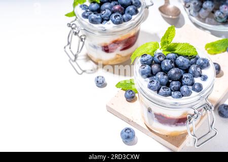 Mehrschichtiges Blaubeerparfait-Dessert, Käsekuchen im Glas mit Vanillekekuchen, cremiger Joghurt, Marmelade und frischer Blaubeere Stockfoto