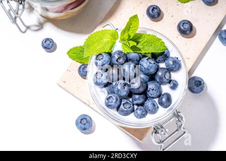 Mehrschichtiges Blaubeerparfait-Dessert, Käsekuchen im Glas mit Vanillekekuchen, cremiger Joghurt, Marmelade und frischer Blaubeere Stockfoto
