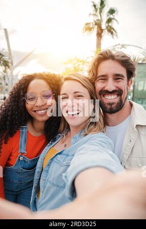 Vertikales Hochformat. Eine Gruppe junger erwachsener Freunde, die lächeln, ein Selfie-Porträt aufnehmen und Spaß miteinander haben. Eine Gruppe von Menschen, die ihre Freundschaft feiern. Zwei Frauen und ein Mann mit positivem Gesichtsausdruck. Hochwertiges Foto Stockfoto