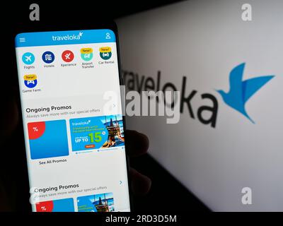 Person mit Smartphone und Webseite des indonesischen Reiseunternehmens Traveloka auf dem Bildschirm vor dem Logo. Konzentrieren Sie sich auf die Mitte des Telefondisplays. Stockfoto